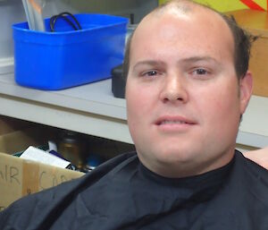 An expeditioner getting his head shaved for charity but only half way!