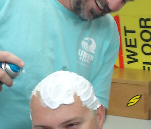 An expeditioner having his head shaved for charity