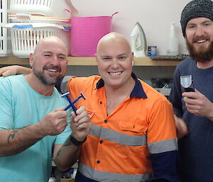 Three expeditioners who have just shaved a head bald