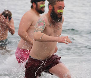 Two male expeditioners sprinting out of the cold water after the swim