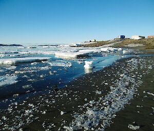 Broken up sea ice in the sea and along the shore on the sand in front of Davis station