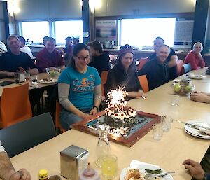 A picture of Nina Dehnard with her birthday cake complete with lit sparklers in the Davis LQ dining room