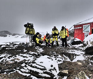 Five Davis expedtioners dressed in full field gear with field packs on their backs outside Watts hut in the Vestfold Hills