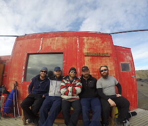 Five Davis summer expeditioners sitting in front of Brookes hut in the Vestfold Hills