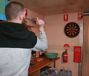 Scott McMillan playing darts at Brookes hut in the Vestfold Hills