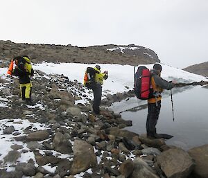 Three expeditioners on a training trip looking out over Lake Stinear in the Vestfold Hills