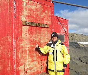 Aaron Stanley pointing to the Brookes hut sign, pleased he was there after hiking from Davis Station on his survival training trip