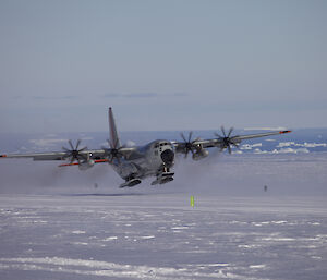 the LC130 takes off from Davis skiway with the icebergs in Prydz Bay in the background