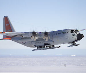The USAP LC130 in the sky above the Davis skiway with an iceberg strewn Prydz Bay in the background