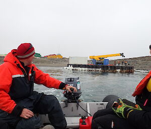 Two expeditioners in a boat with more on the dock waving goodbye