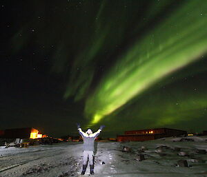 John Parker the doctor at Davis holds his arms up to the sky where the aurora australis illuminates the sky