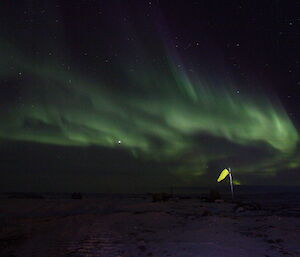 A wind sock up at the heli-hut is illuminated with the aurora australis in the sky above at Davis