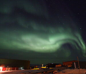 A blueish green aurora australis above the Davis buildings