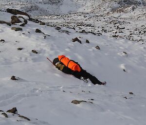 An expeditioner faking exhaustion by lying in the snow near Davis Station