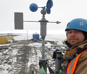 Aasron Stanley takes a photo of himself up at the top of the anemometer mast at Davis Station