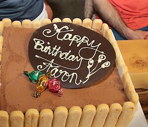 Close-up of the icecream cake lined with sponge-fingers and topped with chocolate in which Aarons name is written