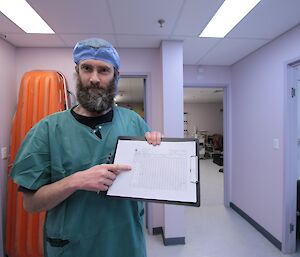 Craig Butsch in surgical scrubs filling out the paperwork for the patient as part of a LSA scenario at Davis