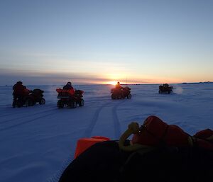 Quad bikes and riders stopped on the sea ice for a break near Davis