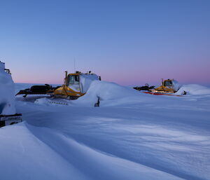 The two snow groomers on the plateau nearly buried in the snow