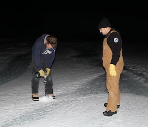 Scott Visser drills the sea ice while Vas Georgiou looks on