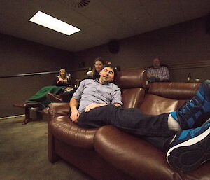 Aaron Stanley relaxing on the couch that is in the cinema at Davis for a special movie night — Lesley Eccles plays up and Jen Proudfoot and Michael Goldstein laugh behind him