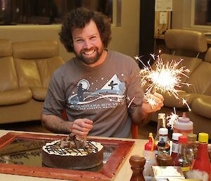 Chris Burns with his birthday cake and holding lit sparklers
