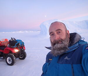 A selfie taken by Darren White with an ice berg and the moon in the background