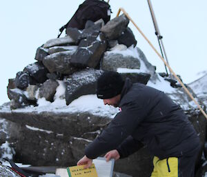 Aaron Stanley looking through the cache of historical items at Sir Hubert Wilkin’s cairn at Walkabout Rocks