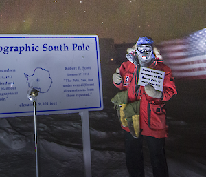 Robert Swharz holding up a notice to welcome Davis to the South Pole (virtually)