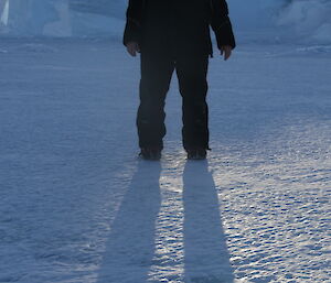 Ali with the sun shining through a hole in an iceberg behind her