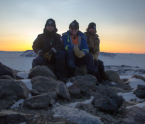 Aaron Stanley, Vas Georgiou, and Chris Burns on top of Anchorage Island with the sunset behind