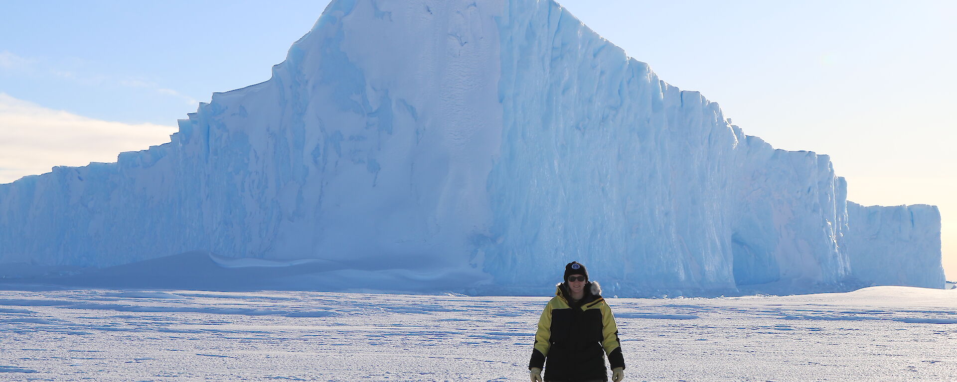 Jen Proudfoot on the sea ice with iceberg backdrop