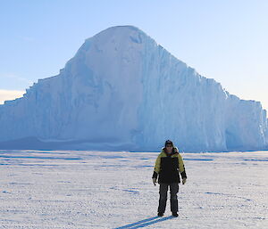 Jen Proudfoot on the sea ice with iceberg backdrop