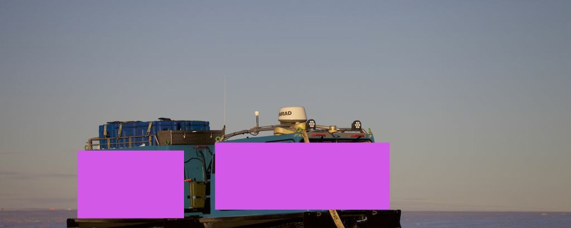 A picture of a Hägglunds painted pink to illustrate what a pink Hagg might look like. This one is depicted on the blue ice of the East Antarctic ice sheet to the south of Davis.