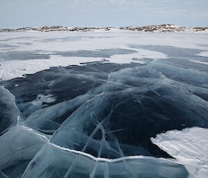 A frozen fresh water lake with cracks in it. The cracks make it look like white curtains