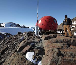 Darren White, an expeditioner standing near a round looking hut