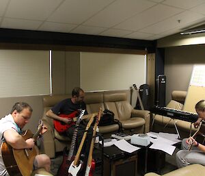 Two expeditioners with guitars trying to play the chords demonstrated by Paul the teacher