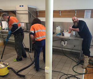 Michael Goldstein uses the pressure cleaner to remove dirt from the kitchen floor while Chris Burns follows behind with the vacuum and Darren White continues cleaning in the Davis kitchen