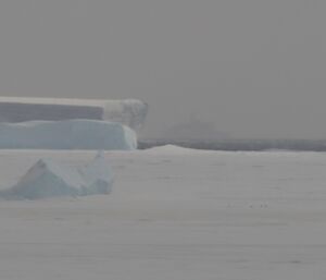 The ghostly image of the Aurora Australis icebreaker ship between the icebergs and through the snow showers off Davis