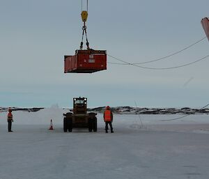 Offloading at the ship — a box is lowered by a crane onto the skidder