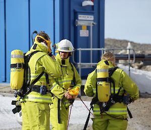 Jock and Kerryn have exited the building on “fire” and are in full fire fighting gear, including breathing apparatus. They are standing outside, surrounded by snow and ice, talking to Lotter who is checking their gauges for how much air they used during the exercise.