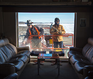 A photo of Mark and Rohan cleaning the windows, taken from inside the building.