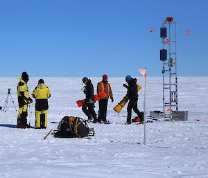 Five people are on the glacier, carrying gear from the tower with the time lapse camera, back to the helicopter pickup site.