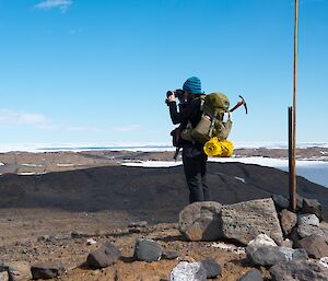 Rachel is standing on a rocky hilltop, looking out over the Vestfold hills with her binoculars.