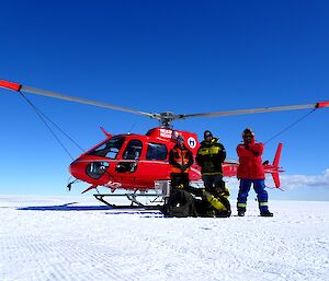 The team of four aircraft ground support officers: Matt, Lance, Trevor and Ross, pose in front of a tied down helicopter