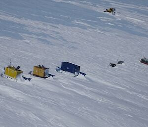 Aerial view of Woop Woop — four shipping containers and some equipment — sitting in snow, on the Antarctic plateau