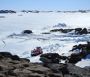 The photo is taken from a high point, looking down on the pink Hägg, travelling on sea-ice.