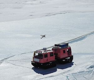 A photo taken from a high point of the pink Hägg travelling over sea-ice,