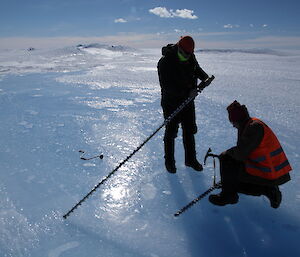 Nick and Lotter prepare a drill for making a hole into the ice.