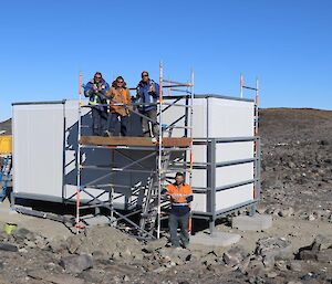 The hut housing the electronics gear is up and a very happy crew of four pose on the scaffolding surrounding the build.